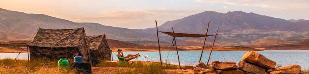 man with feet up looking over lake with view of Atlas mountains