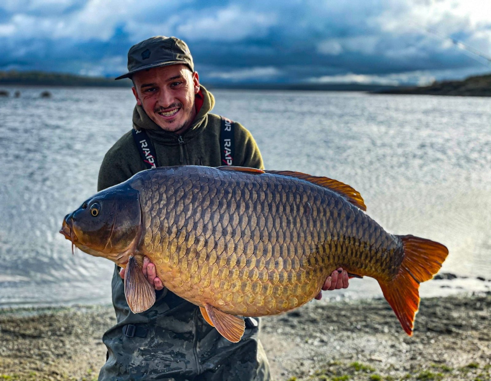 Angler holding carp caught on Orellana Lake in Spain, Europe