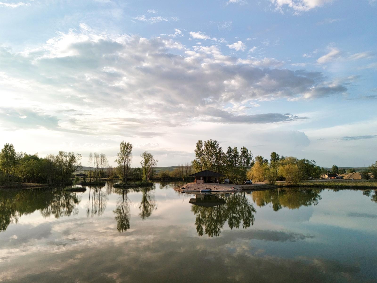 Serene lake with trees and clouds reflection.
