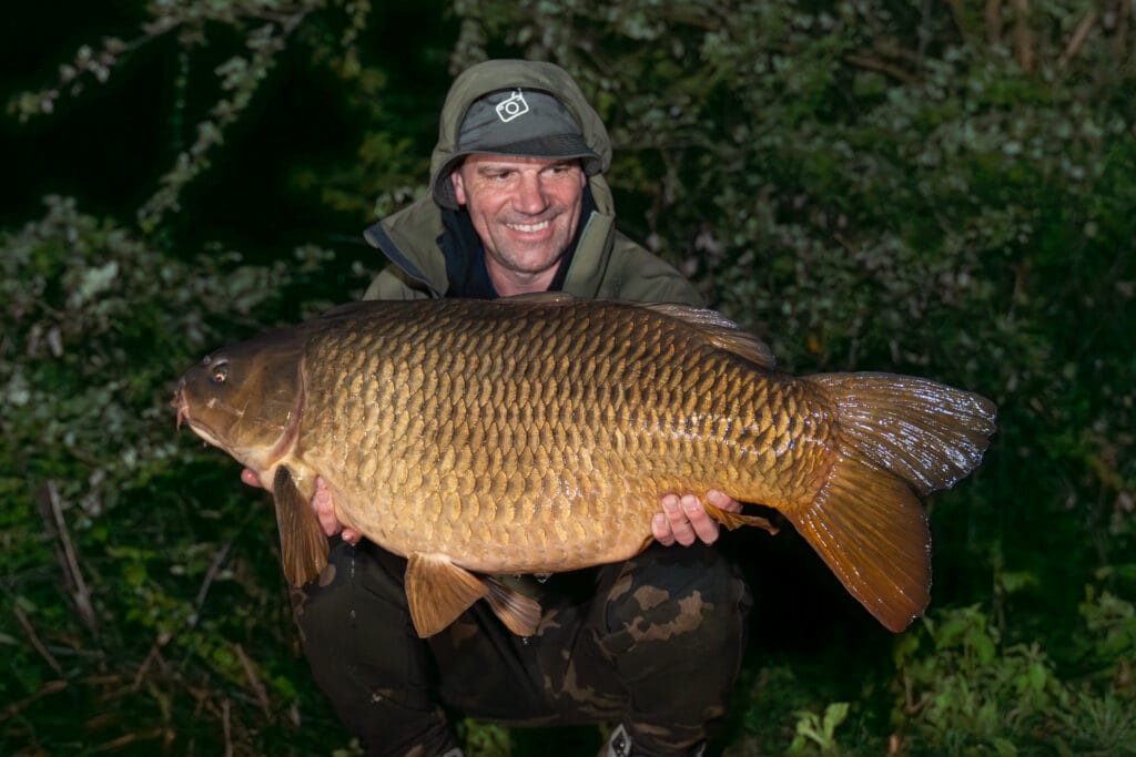 Man holding large carp in outdoor setting