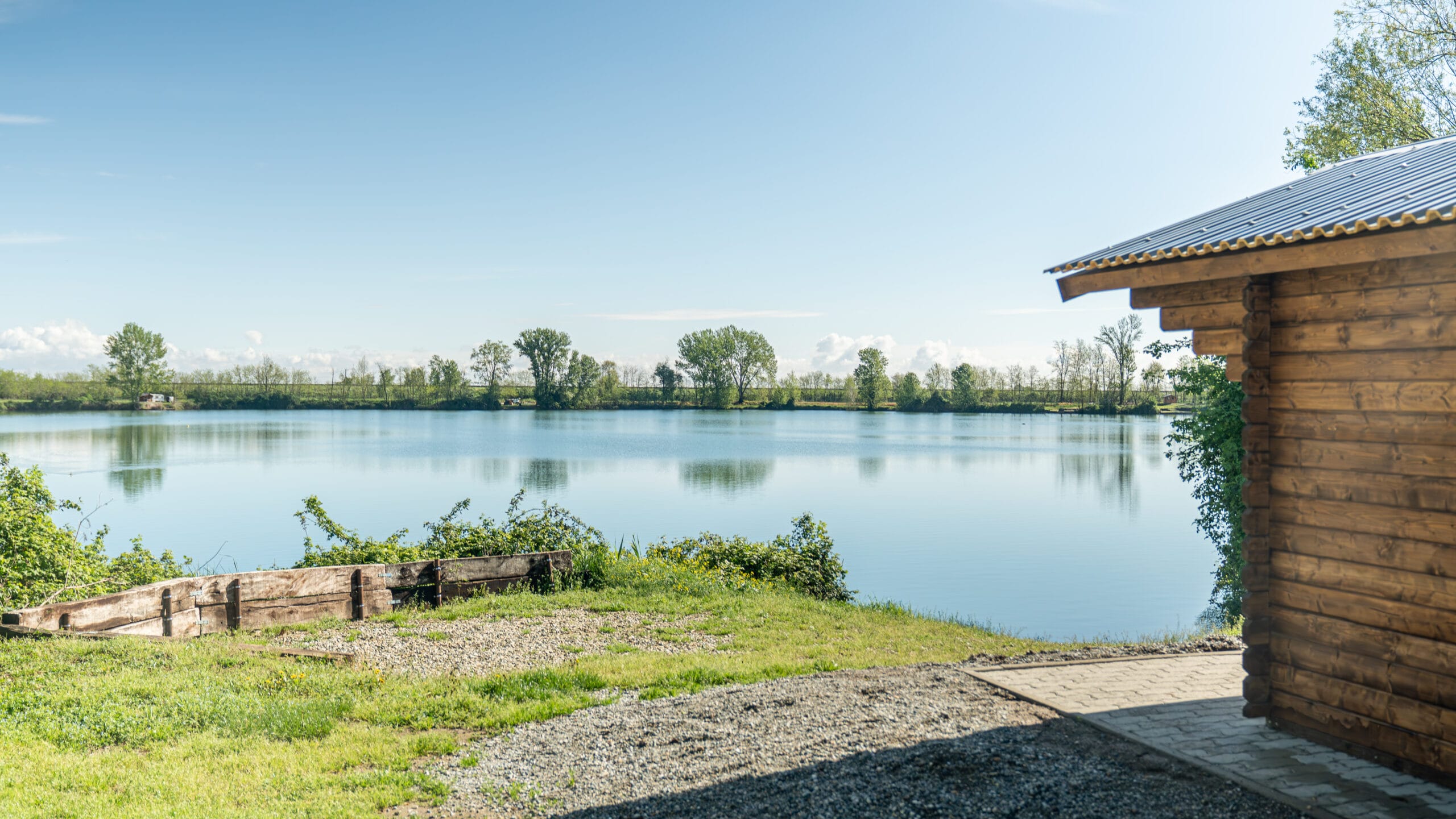 Tranquil lake view with wooden cabin.