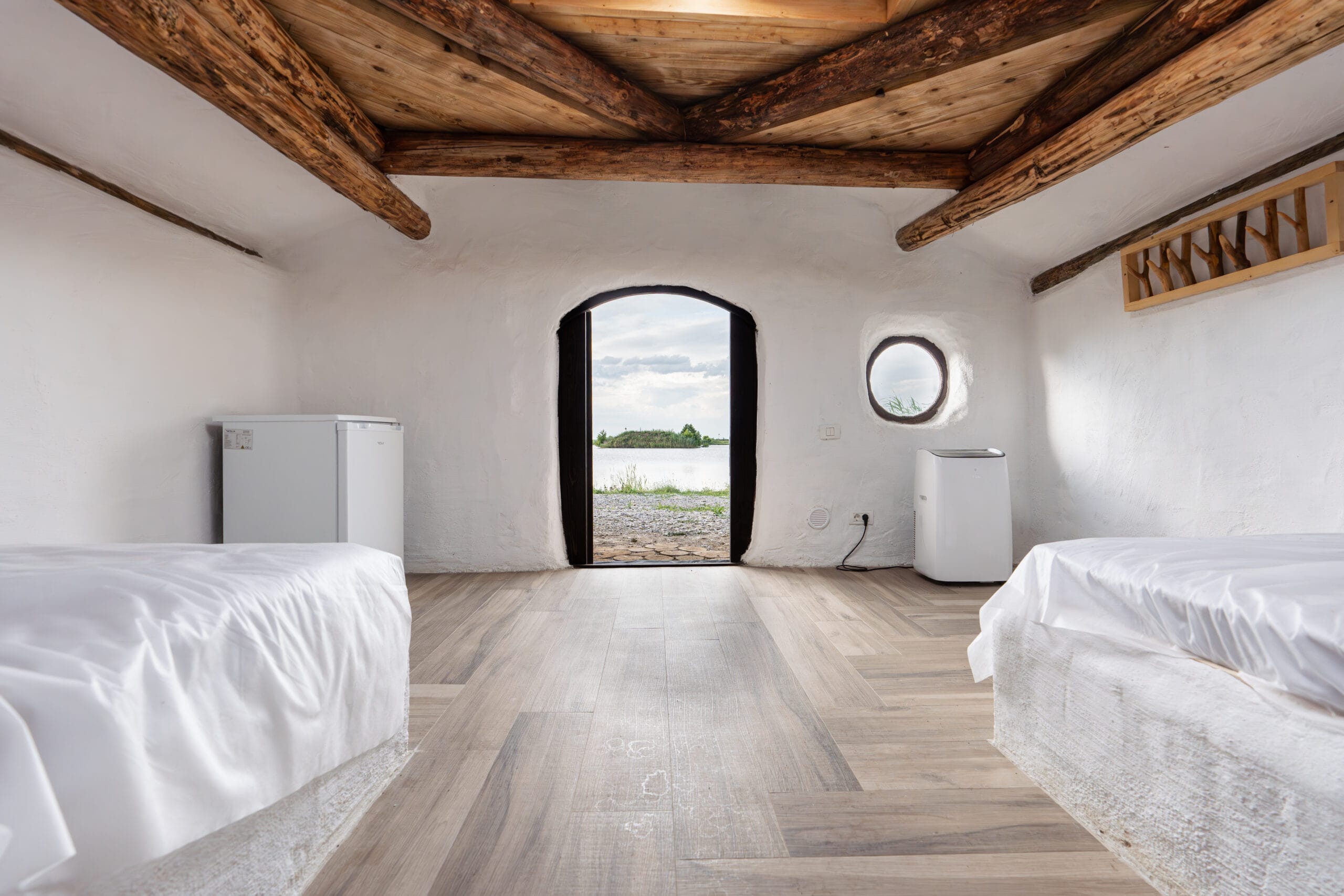 Rustic bedroom with wooden beams and lake view.