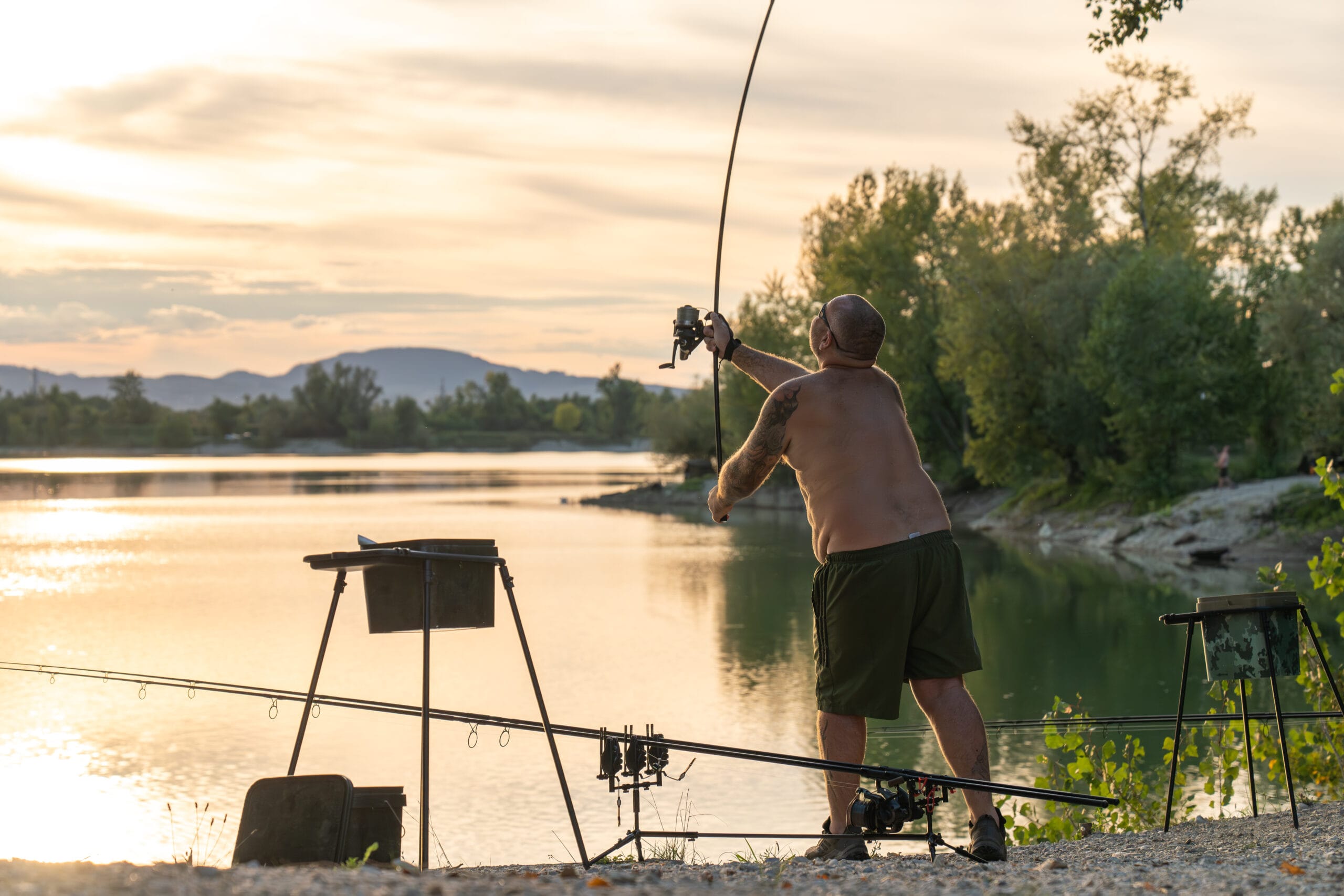 Man fishing by lake during sunset
