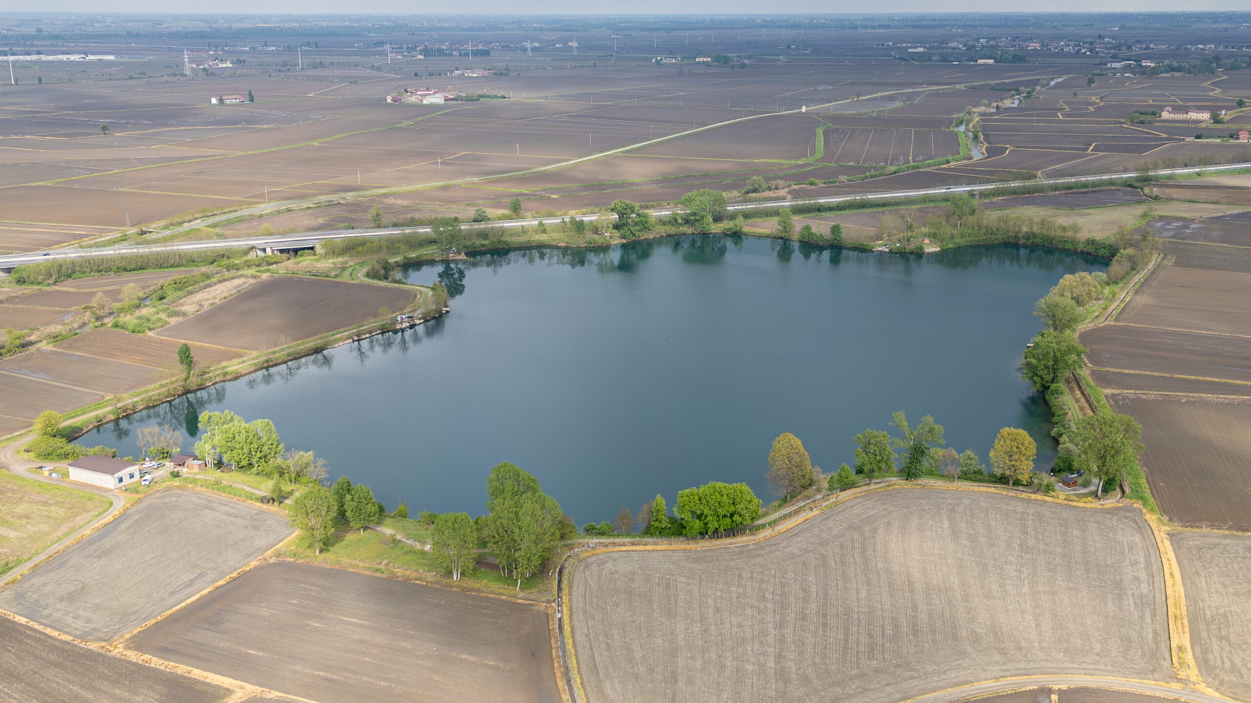 Aerial view of lake amid expansive farmlands.