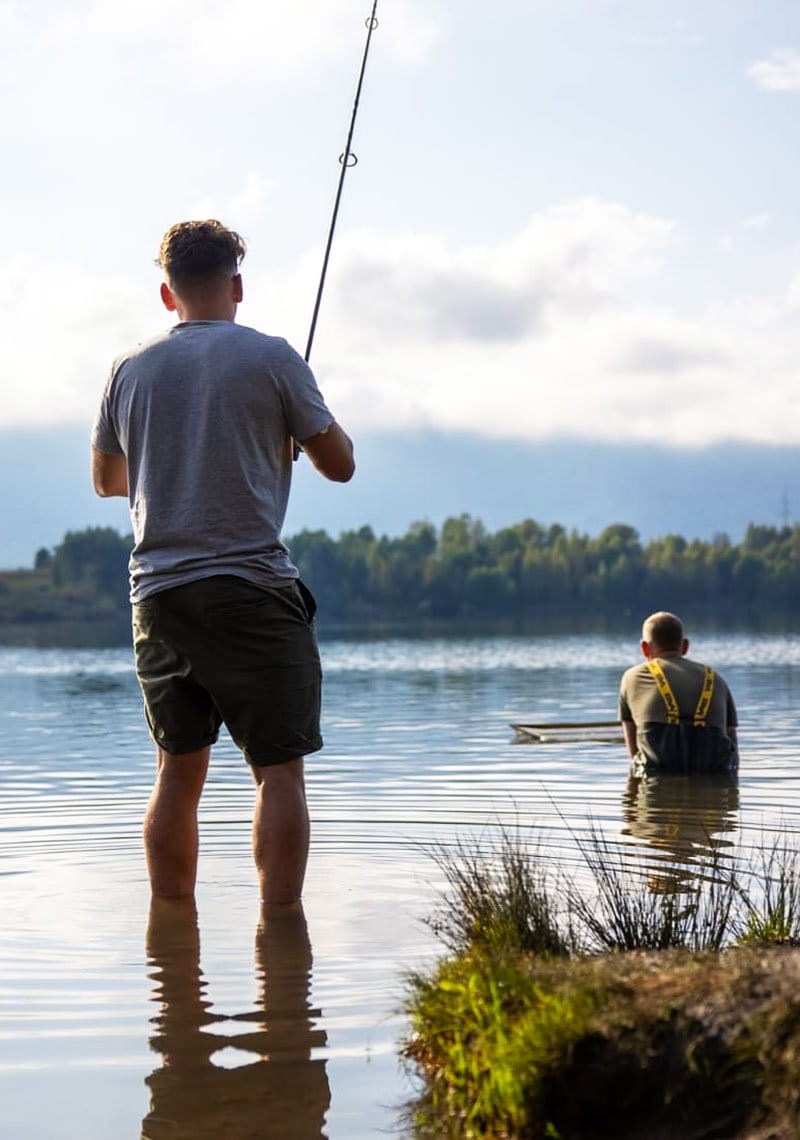 Two men fishing in a serene lake.