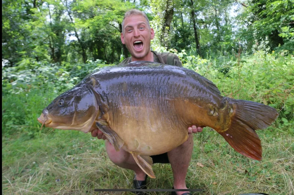 Person holds large carp caught while fishing.