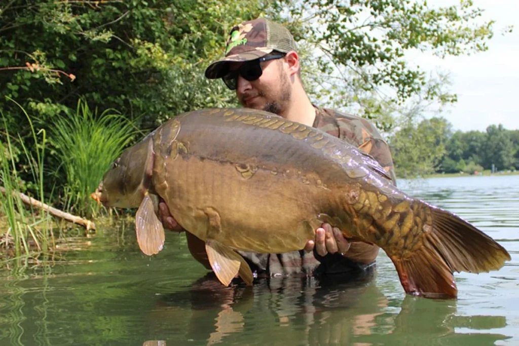Man holding large fish in a lake.
