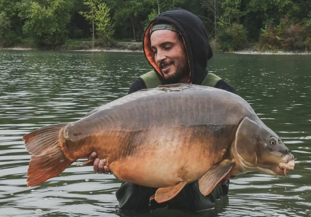 Man holding large carp in lake