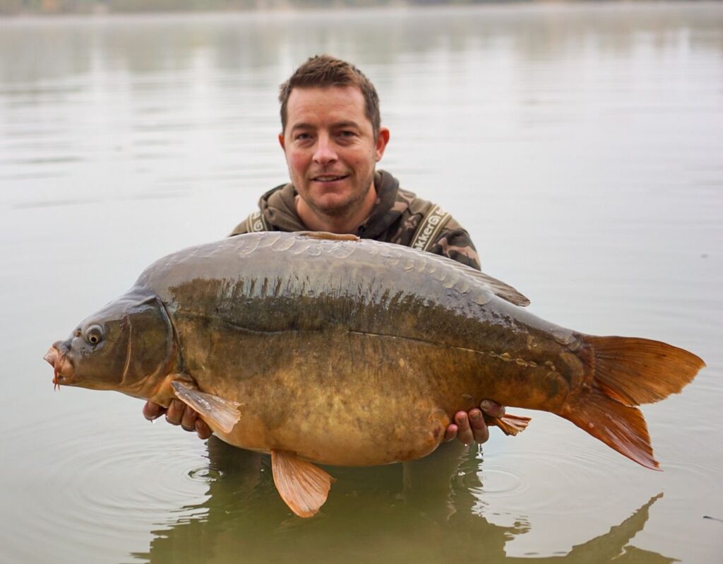 Man holding large carp fish in lake