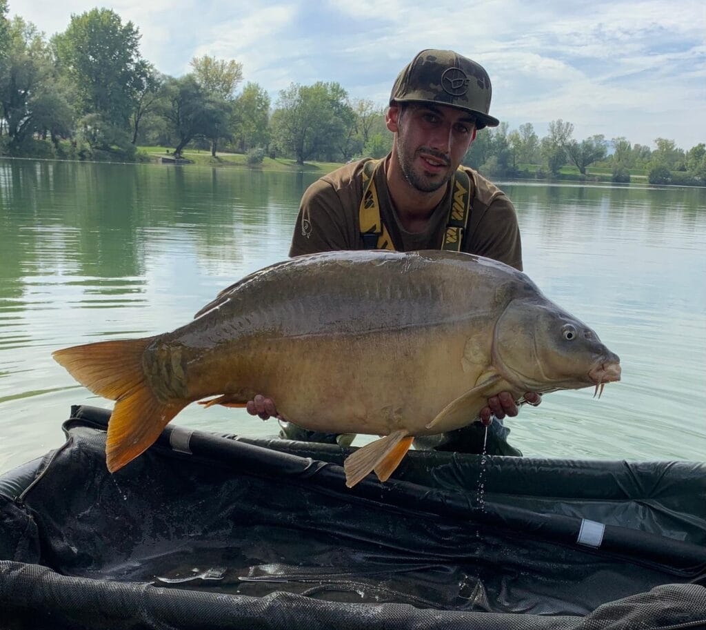 Man holding large fish by the lake.
