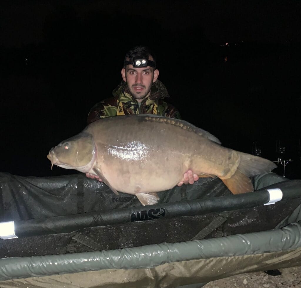 Angler holding large carp at night