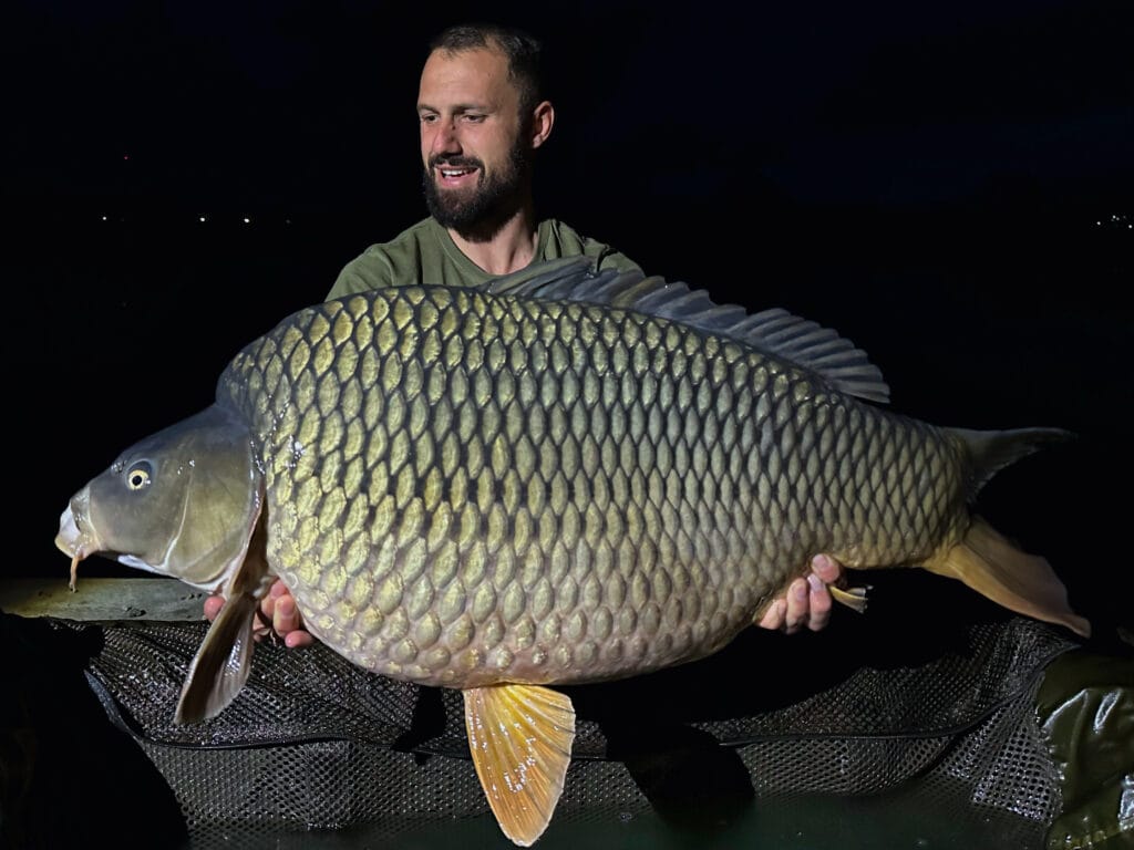 Man holding a large carp fish at night