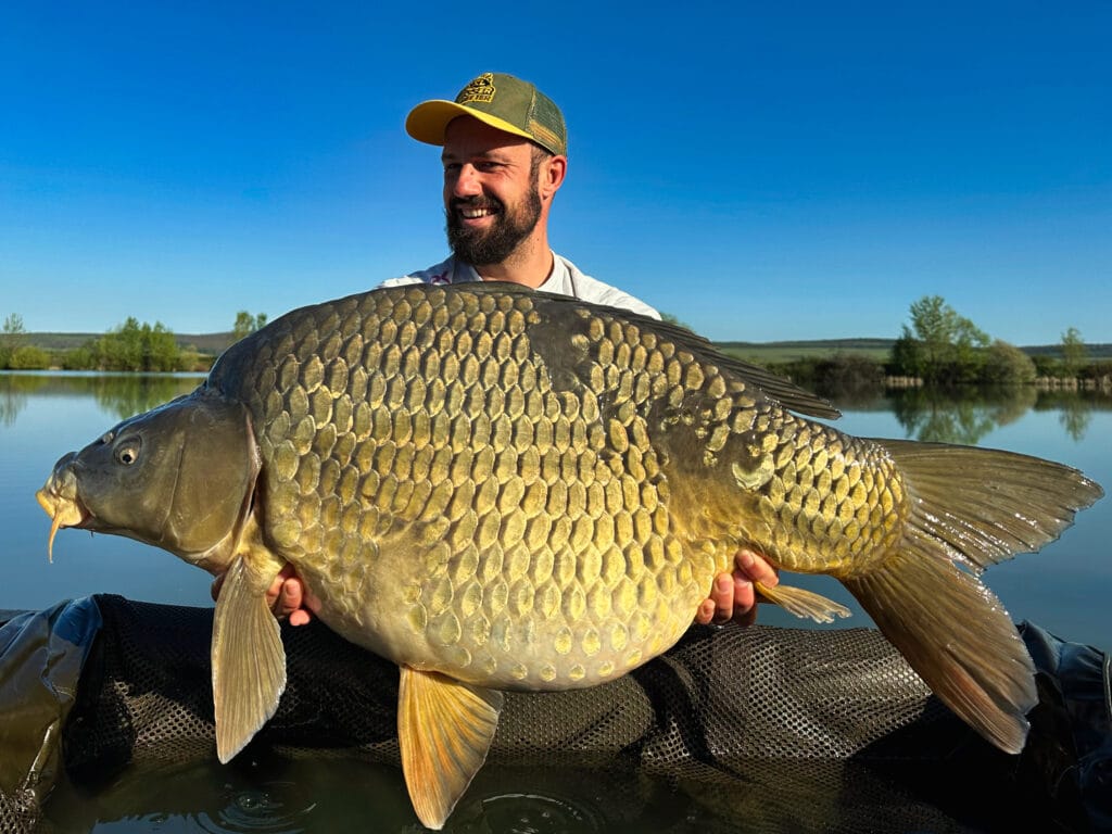 Man holding large fish at lake.