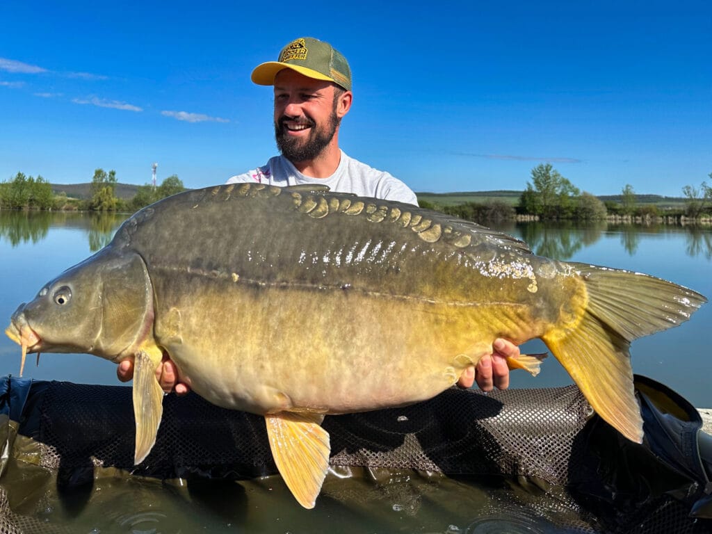 Man holding large carp by the lake