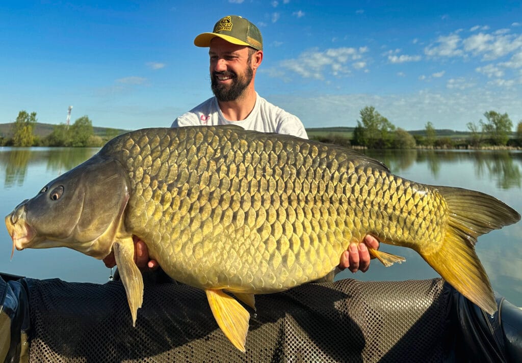 Man holding large carp by lake