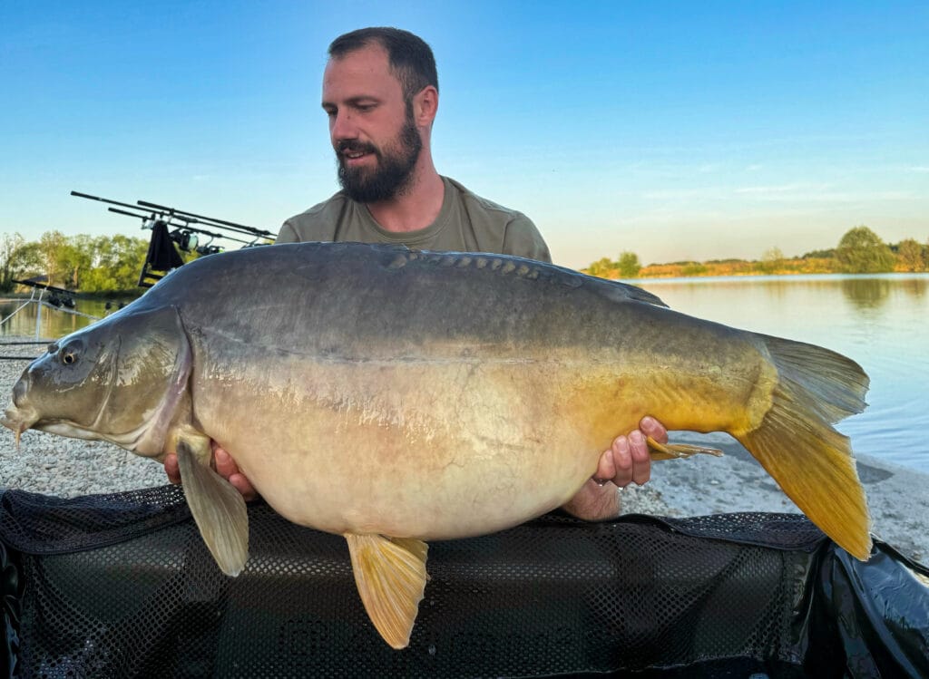 Man holding large carp by a lake