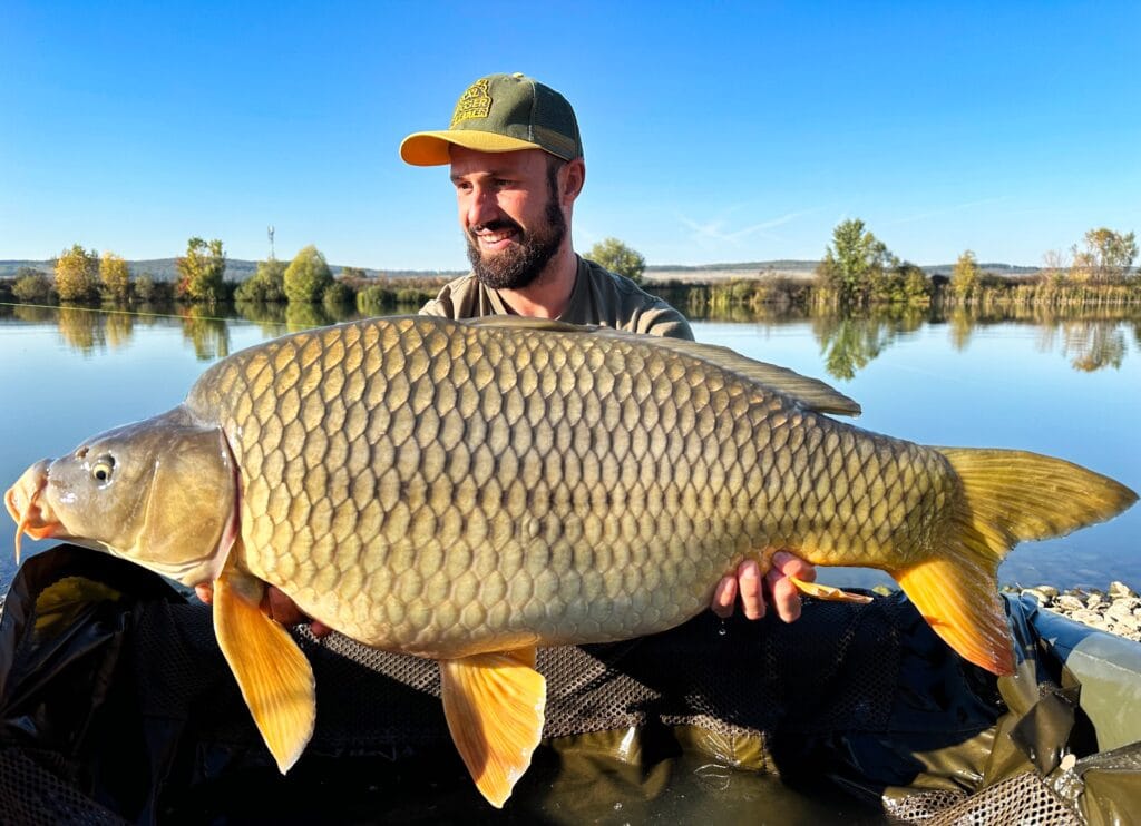 Man holding large carp by a lake