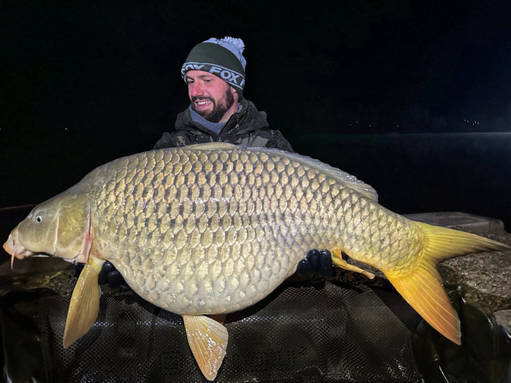 Person holding large carp at night.