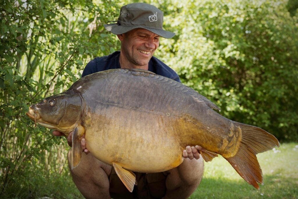 Man holding large carp fish outdoors.