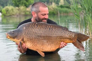 Man holding large carp in lake.