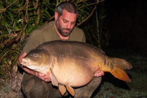 Man holding large fish at night